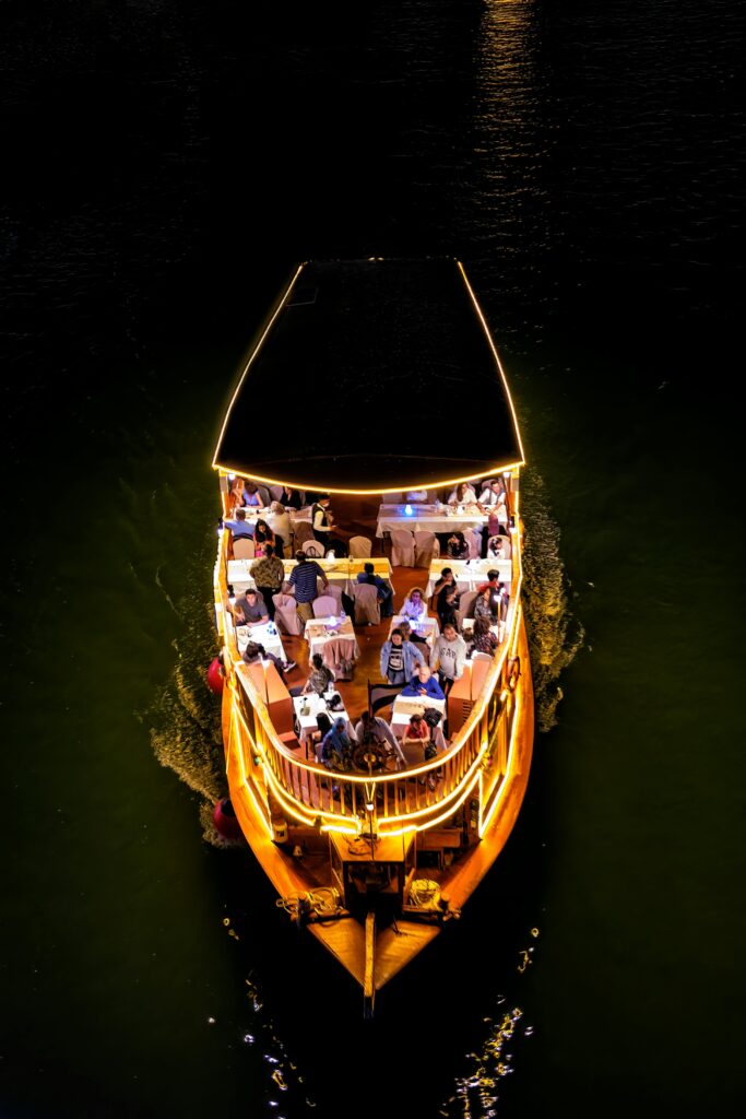 A stunning aerial view of a night cruise boat with illuminated deck and passengers enjoying the ride.